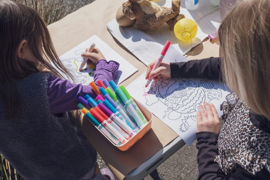 Girls coloring a free printable coloring book with crayons at home